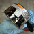 Gloved hand holding IPS-200-HA case, orange WARNING and white CAUTION labels intact on housing