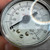 Hand holding the gauge dial showing USE NO OIL warning and SST 316 markings