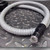 Coiled white armored fiber optic light guide with black ferrule end, ring body at top left