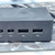 Matte black enclosure with light surface scratching on top face; two Mini DisplayPort and two USB 3.0 Type-A ports visible with dust accumulation in openings.