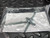 Four zinc-plated machine screws with nuts arranged in an X pattern, accompanied by a printed instruction sheet.