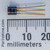 Rear of 2N5961 transistor with circular cross logo, red, blue and violet color bands, millimeter ruler