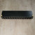 Black crinkle-finish cover with light surface scratches; two brass binding posts and 12 slotted barrier terminals visible; no corrosion.