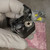 Close view of the PTT button, latch arm, and small screw against a yellow label.