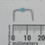 Blue body body spans ~4mm; leads bent downward, tips ~18mm apart. Marking reads "47 J5A." Leads unsoldered, body pristine.