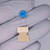 Blue disc body marked '152K / 1KV' in black; straight silver radial leads inserted into a cardboard lead-forming carrier.