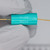 Teal cylindrical bobbin body marked FLUKE and 280974, with partial text visible on lower face. Gold-plated axial leads extend from both ends.