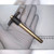 Gold-zinc finish shank with ball detent at tip, dark T-handle with ring pull, approx. 150mm total length per ruler.