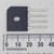 Black square bridge rectifier package with mounting hole and rectangular slot, marked GBU4B and AC pins labeled. Four flat leads show moderate tarnish. Roughly 20mm wide.