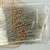 Axial lead resistors with yellow-violet-red-gold band sequence visible on tan bodies, long tinned leads, loose bulk quantity.