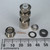 Nickel-plated BNC plug body with knurled coupling ring and white PTFE dielectric, disassembled to show all components: hex nut, center pin, metal washer, flat washer, and rubber gland. Ruler shows body approximately 45mm tall.