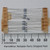 Axial-lead resistors taped to cardboard strips at both ends; blue body with multiband color code visible; leads approximately 28mm long per ruler.