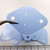 Light blue TO-3 silicone insulator pads, multiple units fanned out; two large mounting holes and two small center holes visible, no markings, flexible.