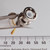Nickel-plated BNC male plug body with knurled coupling ring and white PTFE dielectric visible; gold center pin shown separately. Approximately 20mm body diameter.