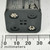 Black plastic body, approx 32mm wide at connector face. Two snap contacts and two empty terminals visible. Coil spring contact at top corner.