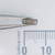 Century Spring G16-CS spring held in tweezers over a scale.