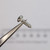Perspective view of a NEWCO 14085 screw held by tweezers.