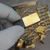 Gold-plated baseplate side of module from electronic scrap lot held in gloved hand.