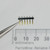 Side profile of Unbranded M1250-0159 dual-row 12-pin header held with tweezers.