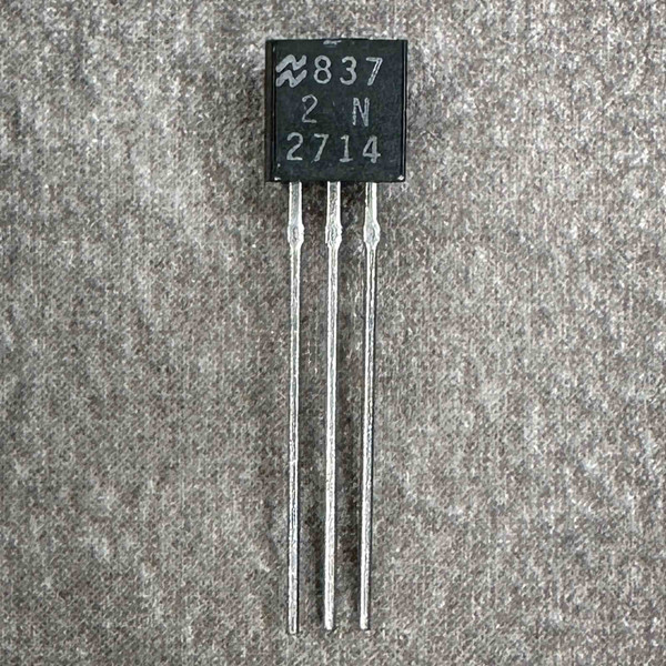 National Semiconductor 2N2714 transistor package marking close-up, three leads on gray fabric background.