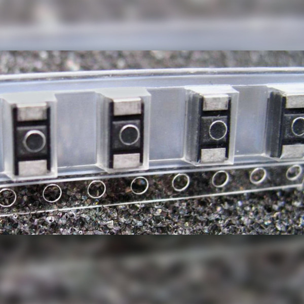 Vishay 293D226X9016C2T tantalum SMD capacitors seated in embossed carrier tape.