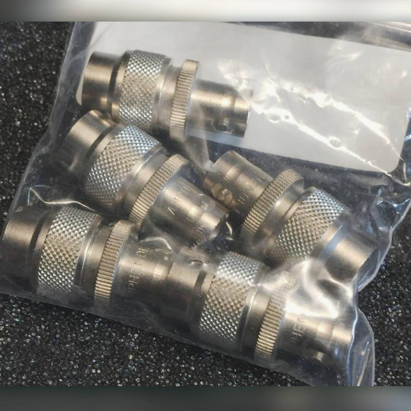 Several Amphenol TNC to BNC adapters bagged together on a black background.