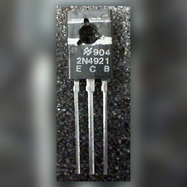 National Semiconductor 2N4921 transistor marked E C B, three leads, on a dark speckled surface