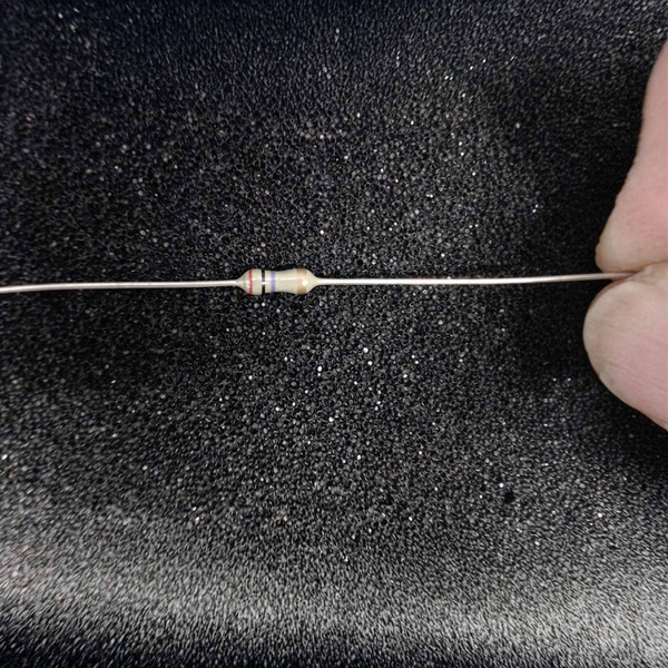 Resistor body clean, leads straight and untarnished, color bands red black violet gold clearly visible.