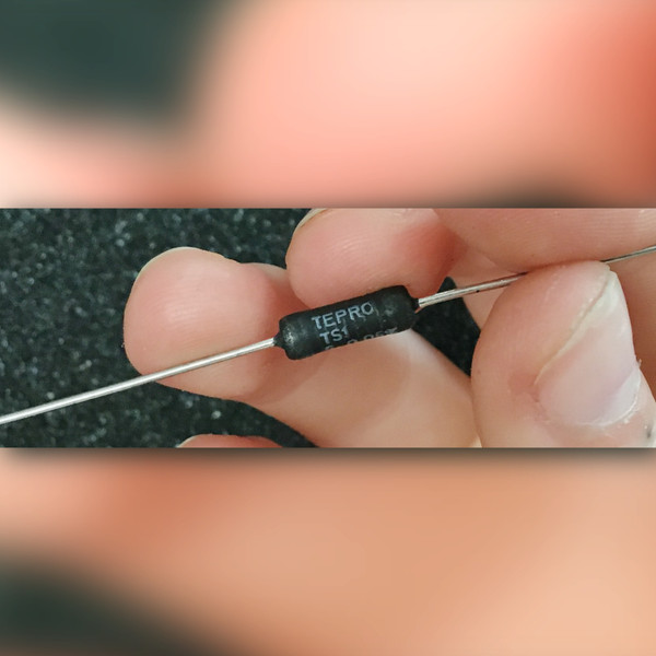 Fingers holding black axial TEPRO resistor marked 5 ohm 0.05% with numeric code