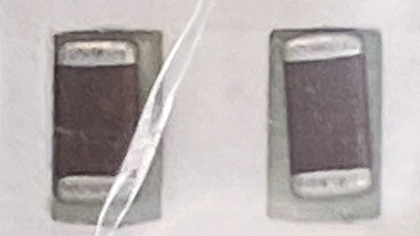 Macro of two ceramic chip capacitors behind a wrinkle in clear bag film