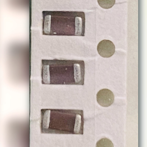 Five brown ceramic chip capacitors in a row, a sixth cut off at the edge