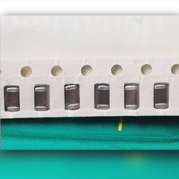 Close view of two whole and two partial brown ceramic chip capacitors with silver-grey end terminations