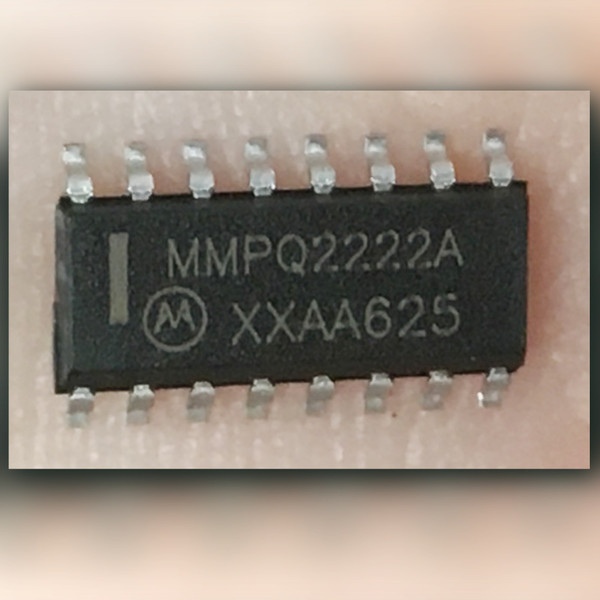 Motorola MMPQ2222A quad NPN transistor array held on a fingertip, top marking visible