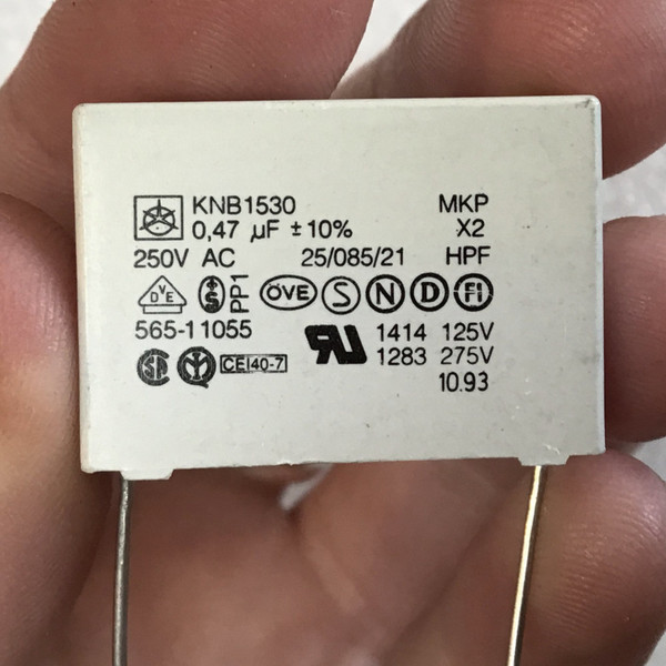 Printed face held in fingers: KNB1530, 0,47 uF, 250V AC, MKP, X2 and agency marks
