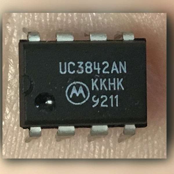 Black 8-pin DIP on a light crinkled surface marked UC3842AN with Motorola M logo and 9211