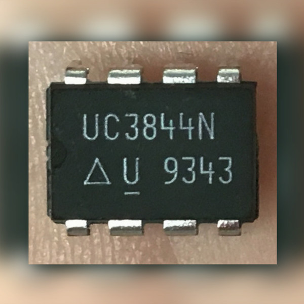 Black 8-pin DIP held in a palm, marked UC3844N with Unitrode triangle-U logo and 9343