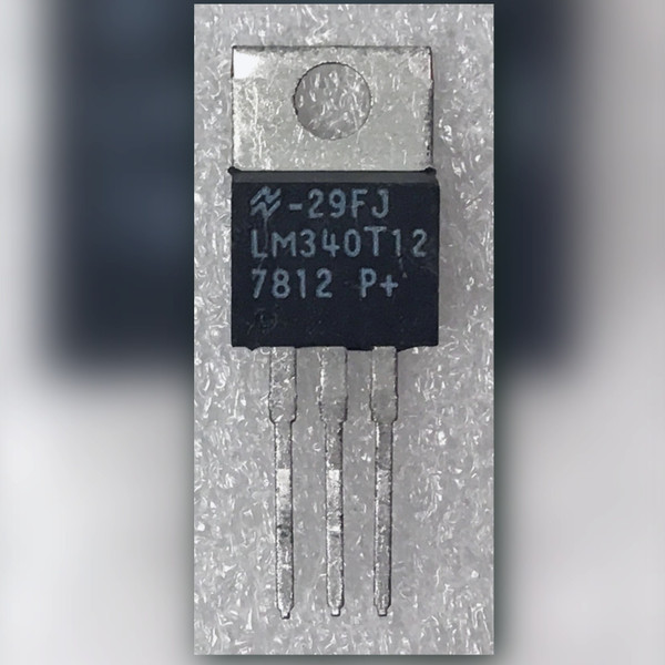 Front view of LM340T12 TO-220 regulator, markings legible, three straight untrimmed leads