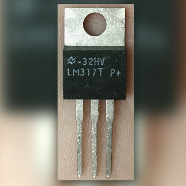 TO-220 regulator held in fingers, marked with the National Semiconductor logo and 32HV above LM317T P+