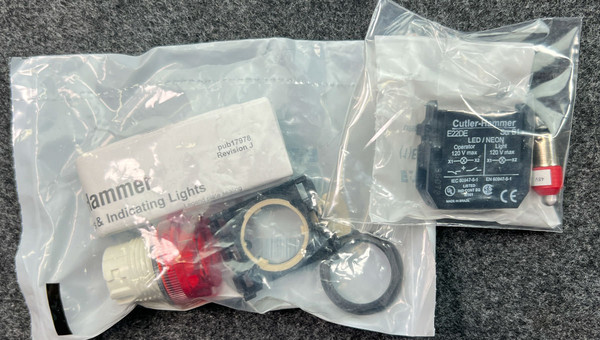 Two factory-sealed poly bags containing indicator hardware, LED lamp, and red bezel; Cutler-Hammer label visible on right bag.