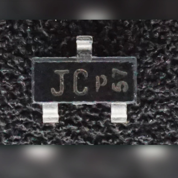 Black SOT-23 diode on a dark textured backdrop, top face marked JC with smaller p57