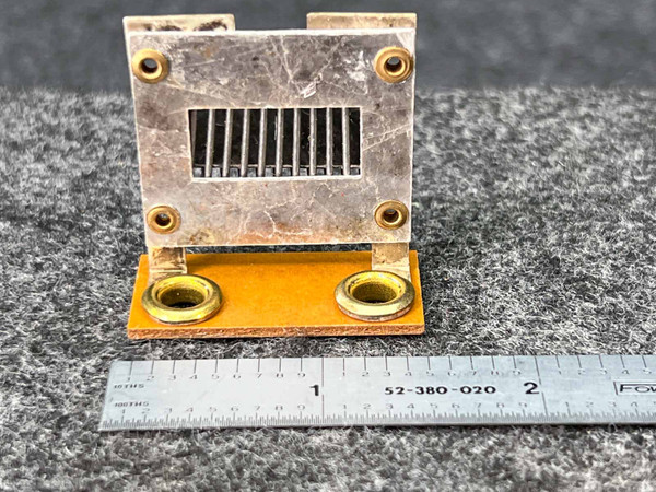 A Federal Pacific F1.8 Thermal Overload Heater Element is displayed upright against a grey background, showcasing its vintage industrial design. The primary component features a rectangular, tarnished silvercolored metal housing with a central rectangular cutout containing multiple vertical heating fins or vents. Four small brass rivets secure the metal frame to a thicker, rectangular yellowishorange phenolic or insulating base. This base has two larger brass grommets, likely serving as electrical connection terminals. A metal ruler along the bottom edge provides scale, indicating the heater element is approximately 1.5 inches wide. This electrical circuit protection component is a critical replacement part for overload relays.