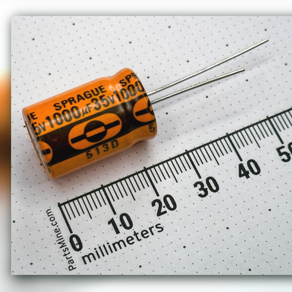 Angled Sprague 513D 1000uF 35V orange capacitor with millimeter rule alongside