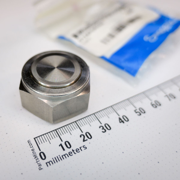Angled close-up of Swagelok SS-1410-P stainless plug beside millimeter ruler, blue factory bag behind