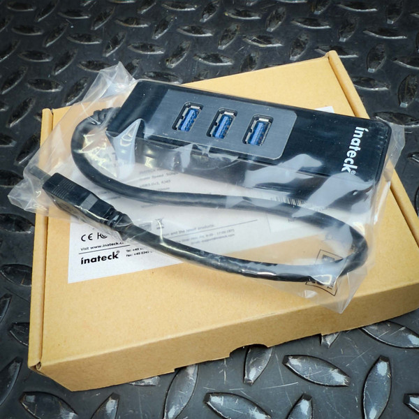 Inateck HBU3VL3-4 USB 3.0 hub in factory poly bag resting on kraft retail box