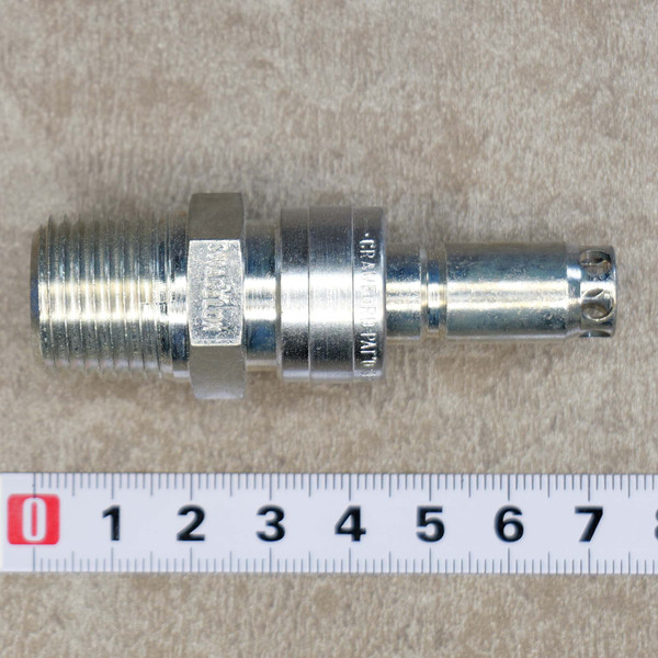 Swagelok QC200 Quick Connect fitting, 1/2 MPT  1/2, a silvertoned metal industrial connector, displayed horizontally on a textured light brown background with a measurement ruler for scale. The fitting features a male pipe thread (MPT) on the left, a hexagonal section with 'SWAGELOK' clearly visible, and a quick connect plug or stem on the right with small circular indentations at the tip. 'CRAWFORD PAT'D' is also visible on the quick connect body, detailing this durable metal fitting.
