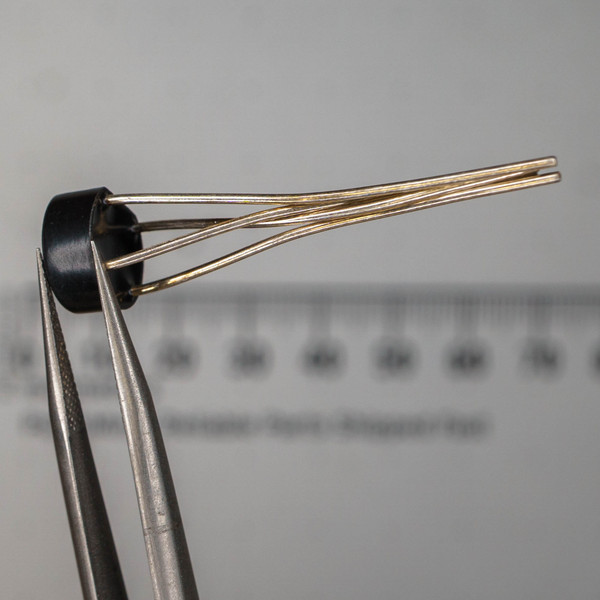 Bridge rectifier showing slightly bent silver-plated leads with light tarnish, black WOG package no visible markings.