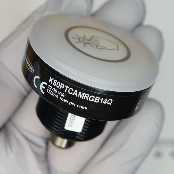 Label reads K50PTCAMRGB14Q, 12-30 Vdc, 150mA max per color, CE marked. M12 connector clean, lens unmarked, barcode label partially legible.