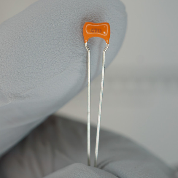 Orange ceramic disc body marked "470," both leads straight, clean, and unsoldered. Coating intact with no chips or cracks visible.