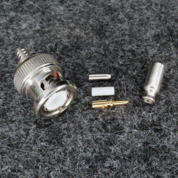 Disassembled connector body with knurled nickel shell, white PTFE dielectric, gold-plated center pin, silver ferrule, and crimp sleeve — all components present.