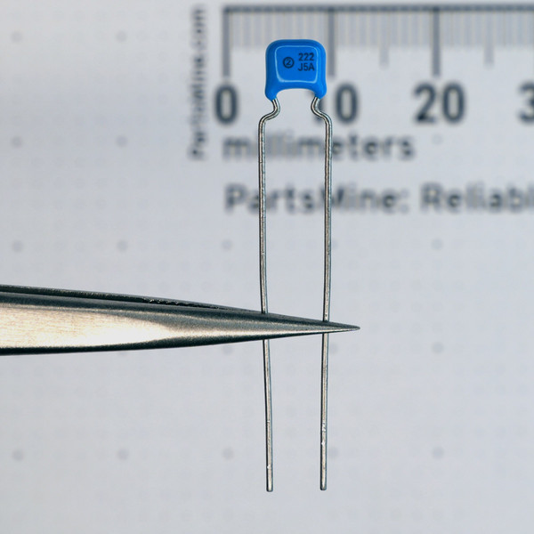 Close-up of 222-J5A blue radial capacitor showing markings and lead form.